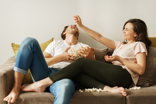 Glückliches Paar, das zu Hause Popcorn isst und Film schaut