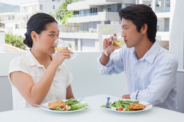 Glückliches Paar, das zusammen mit Weißwein eine Mahlzeit hat