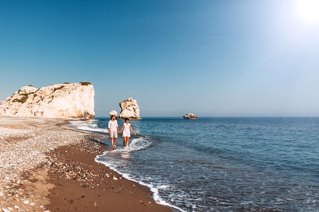 Glückliches Paar Händchen haltend am Sandstrand spazieren. Verliebtes Paar bei Sonnenuntergang am Meer. Verliebtes Paar im Urlaub. Reise-Urlaub-Konzept. Romantisches Paar bei einem Strandspaziergang bei Sonnenuntergang