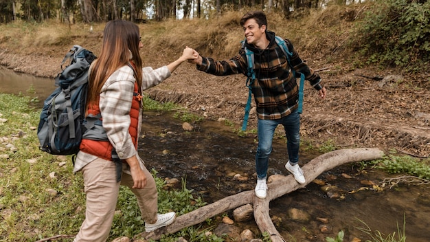 Glückliches Paar im Wald, der Hände auf einer Brücke hält