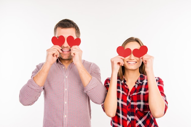 Glückliches Paar in der Liebe, die Augen hinter Papierherzen versteckt