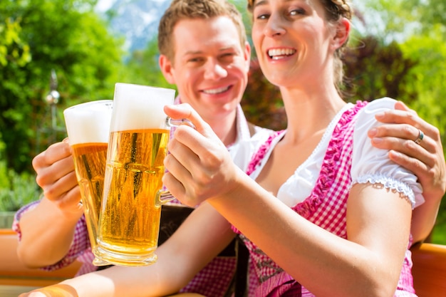 Foto glückliches paar in trinkendem bier des biergartens