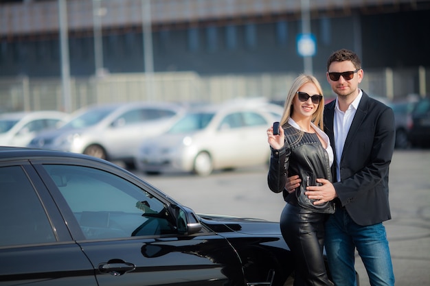 Glückliches Paar kaufen neues modernes schwarzes Auto