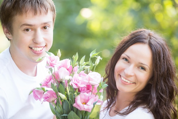 Glückliches Paar mit Blumen im Frühlingspark