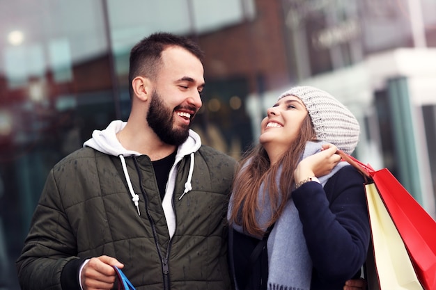 glückliches Paar mit Einkaufstüten nach dem Einkaufen in der Stadt lächelnd und umarmt