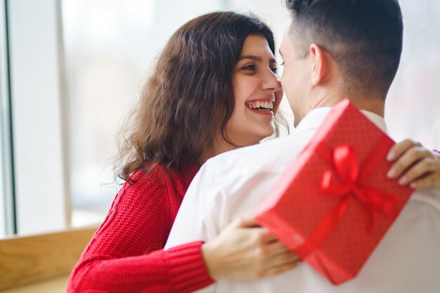 Glückliches Paar mit Geschenkumarmung Rote Geschenkbox in den Händen eines verliebten Paares Valentinstag