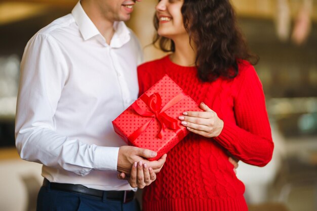 Glückliches Paar mit Geschenkumarmung Rote Geschenkbox in den Händen eines verliebten Paares Valentinstag