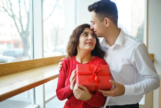 Glückliches Paar mit Geschenkumarmung Rote Geschenkbox in den Händen eines verliebten Paares Valentinstag