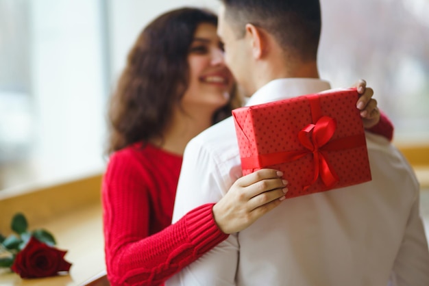 Glückliches Paar mit Geschenkumarmung Rote Geschenkbox in den Händen eines verliebten Paares Valentinstag