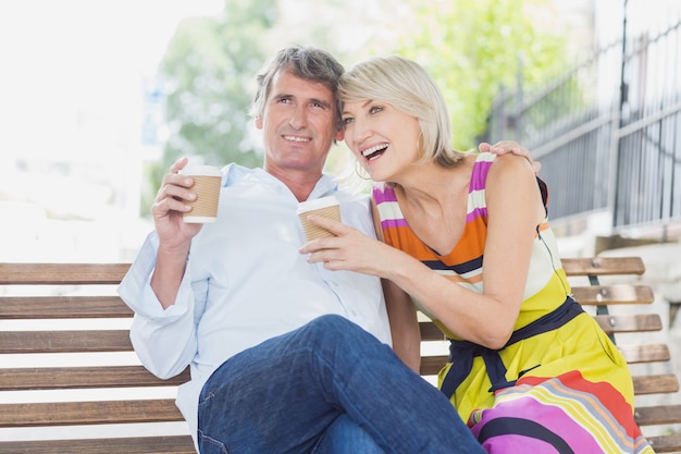 Glückliches Paar mit Kaffeetassen im Park
