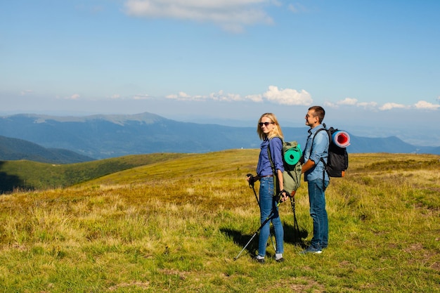 Glückliches Paar mit Wanderstöcken und Rucksäcken in den Bergen