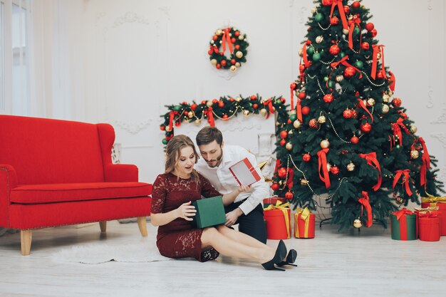 Glückliches Paar mit Weihnachtsgeschenk lokalisiert über Lichthintergrund