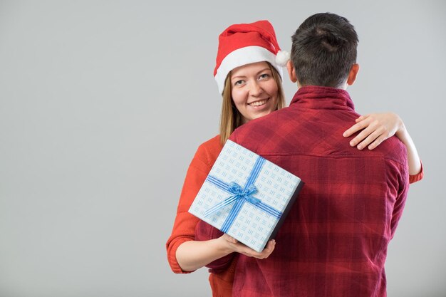 Glückliches Paar mit Weihnachtsgeschenk über grauem Hintergrund isoliert