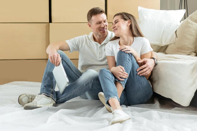 Glückliches Paar sitzt in der Nähe von Kisten in einer neuen Wohnung