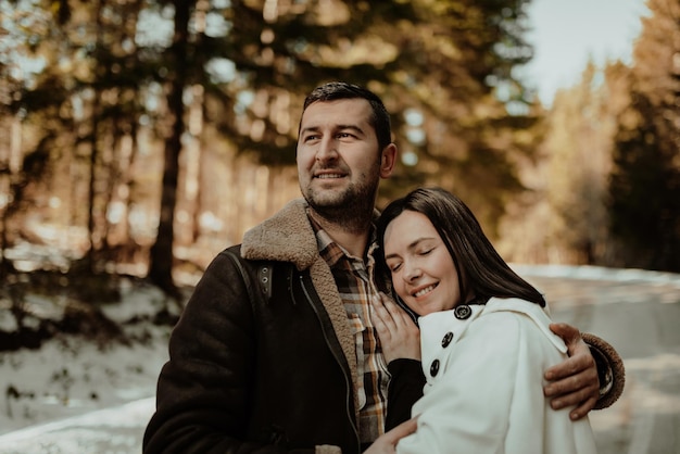 Glückliches Paar umarmt und lächelt draußen im verschneiten Park Selektiver Fokus