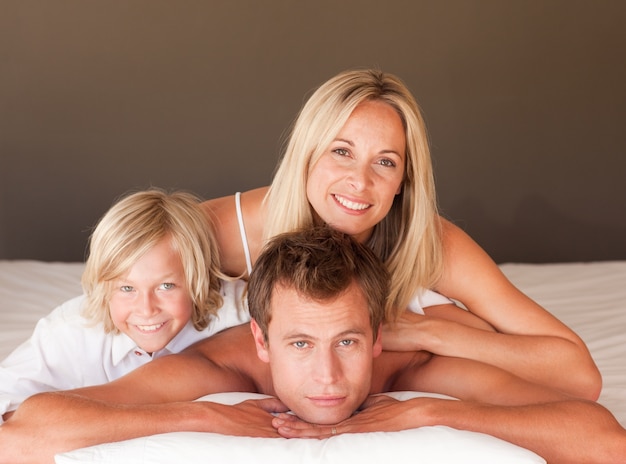 Glückliches Paar und Sohn, die zusammen im Bett genießen