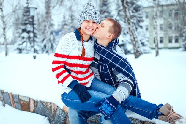 Glückliches Paar von Männern und Frauen, die sich umarmen und Spaß daran haben, draußen warme Kleidung zu tragen
