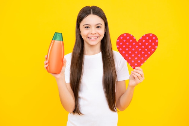 Glückliches Porträt des Kindes mit Shampoo-Conditioner Tägliche kosmetische Pflege Teenager-Kind 12 13 14 Jahre alt Halten Sie eine Flasche Haar- und Hautpflege Schönheit, Gesundheit und Kosmetik Lächelndes Mädchen