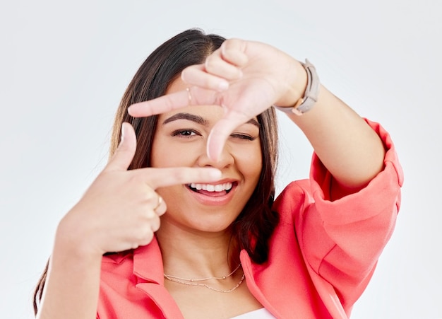 Glückliches Porträt einer Frau mit Handrahmen und gegen einen weißen Hintergrund Soziale Medien oder Kreativität Gesicht oder Lächeln und weibliche Person posieren mit Gesten für perfekte Fotografie im Studio-Hintergrund