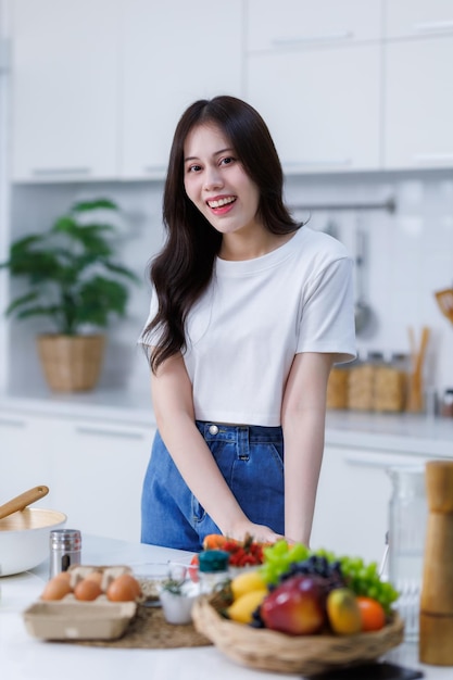 Glückliches Porträt einer jungen asiatischen Frau, die einen Korb mit Gemüse in der Hand hält