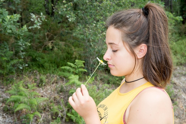 Glückliches Profilporträt der jungen Frau mit den Blumen, die Natur im Feld genießen