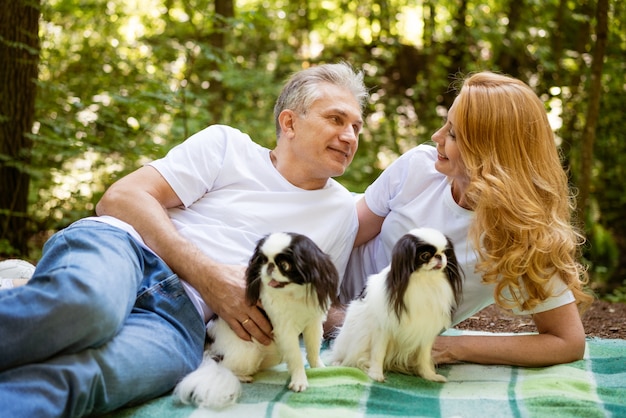 Glückliches reifes verheiratetes Paar im Wald liegen auf Decke mit Hund