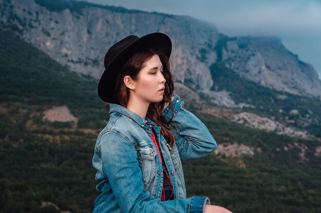 Glückliches reisendes Hipster-Mädchen auf bewölkten Bergen