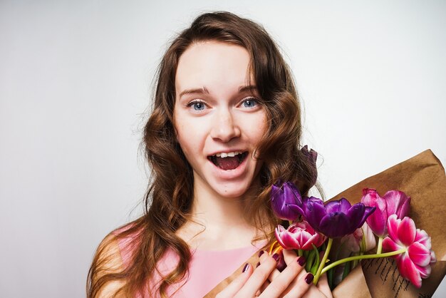 Glückliches schönes blauäugiges Mädchen, das einen Blumenstrauß hält und den Weltfrauentag feiert