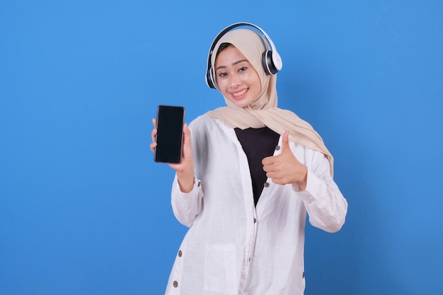 Glückliches schönes Mädchen, das Musik in drahtlosen Kopfhörern tanzt und hört, Smartphone haltend