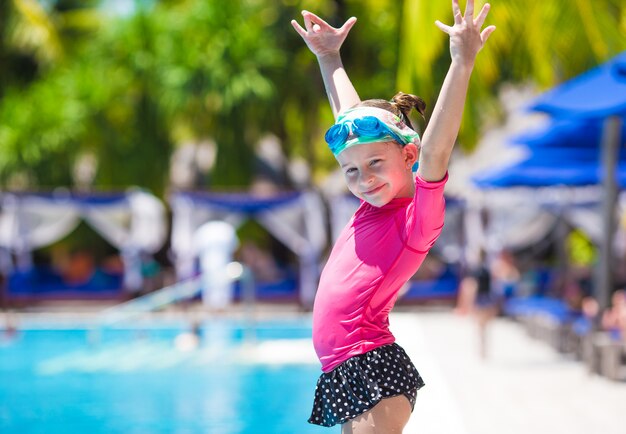 Glückliches schönes Mädchen, das Spaß Swimmingpool im im Freien hat