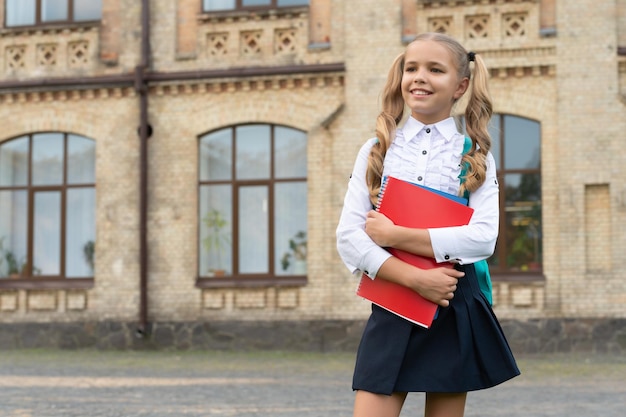 Glückliches Schulkind in einheitlicher Backtoschool mit Büchern und Rucksackkopierraum