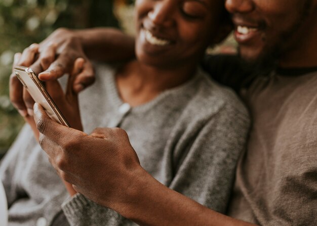 Glückliches schwarzes Paar mit einem Smartphone