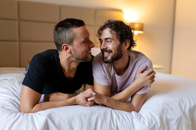 Glückliches schwules Paar, das sich zu Hause auf dem Bett hinlegt und umarmt und flirtet LGBT-schwules Paar liebt Momente Glückskonzept