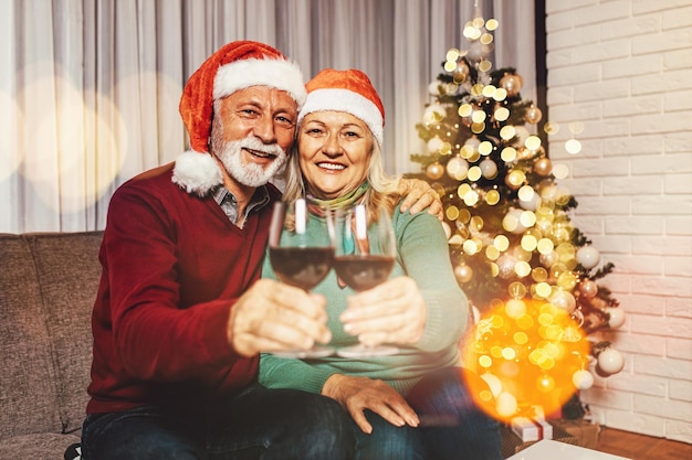 Glückliches Seniorenpaar, das Wein trinkt und das neue Jahr zu Hause feiert.