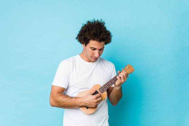 Glückliches spielendes ukelele des jungen kaukasischen Mannes lokalisiert