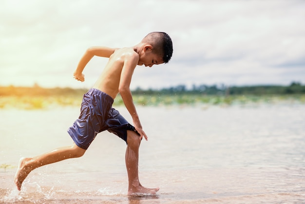 Glückliches spielendes Wasser des kleinen Jungen im Fluss