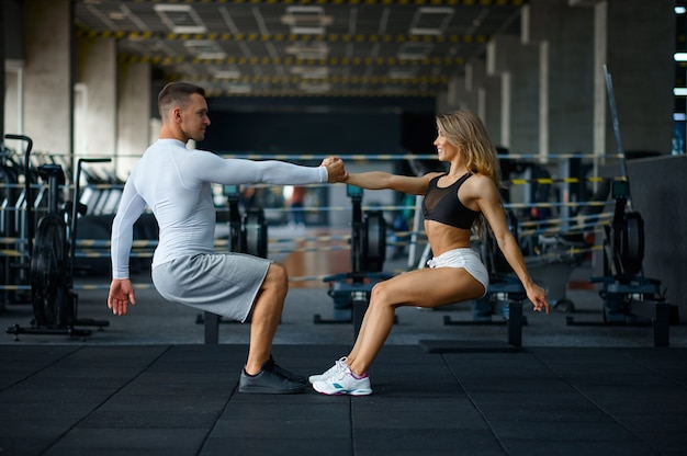 Glückliches sportliches Paar macht Liegestütze, trainiert im Fitnessstudio