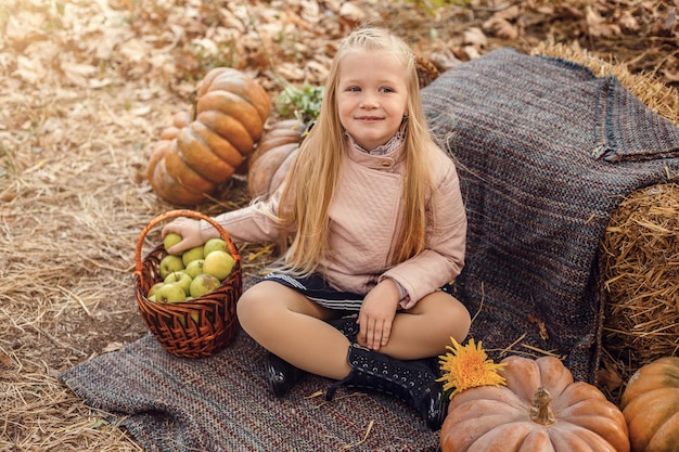 Glückliches süßes Mädchen im Herbst Herbst im Freien Erntefest feiern Kind Mädchen frisches Gemüse ernten rustikalen Stil Kind präsentiert Ernte Gemüsegarten Holzhintergrund Herbsternte Urlaub