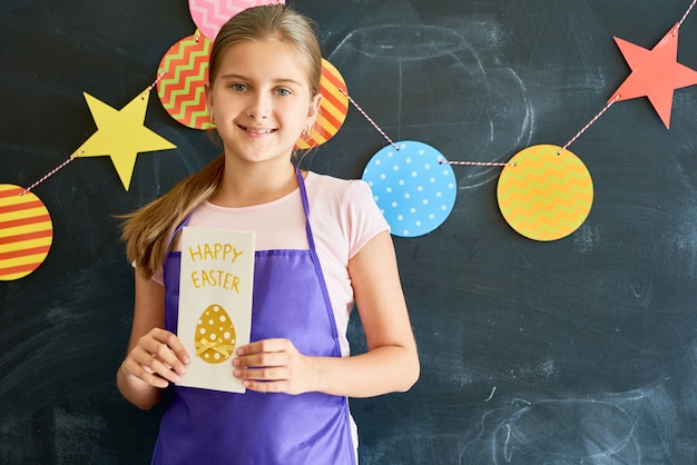 Glückliches Teenager-Mädchen, das Ostern-Grußkarte hält