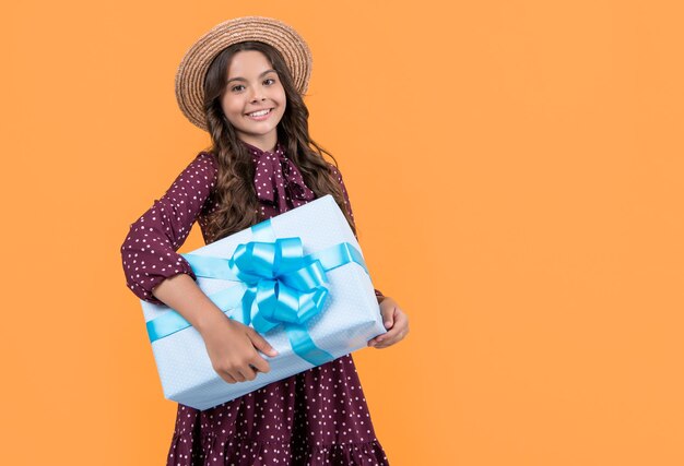 glückliches Teenager-Mädchen mit Geschenkkiste auf gelbem Hintergrund Kopierraum