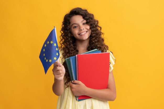 Glückliches Teenager-Mädchen studiert mit Schularbeitsbüchern und hält das Schengen-Visum der Flagge der Europäischen Union