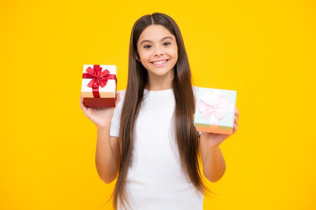 Glückliches Teenager-Porträt Lächelndes Mädchen im T-Shirt Teenager-Kind mit Geschenkbox auf gelbem, isoliertem Hintergrund Geschenk für Kindergeburtstag Sommerferien