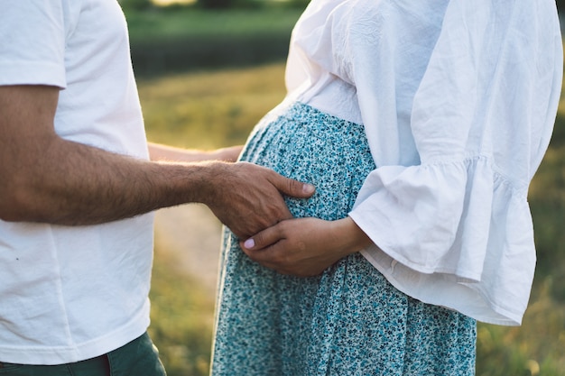 Glückliches und junges schwangeres Paar im Freien
