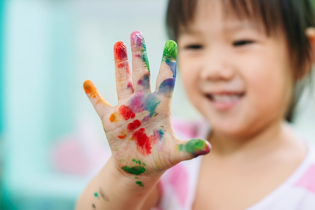 Glückliches und nettes Mädchen benutzt die Hände und die Finger für Fingermalereikunstarbeit.