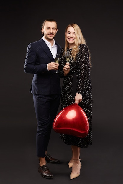 Foto glückliches valentinstagkonzept verliebtes paar mit champagnergläsern und rotem herzförmigem luftballon