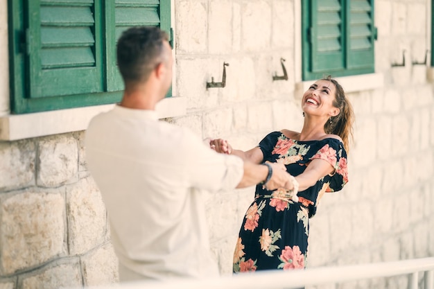 Glückliches verliebtes Paar, das Spaß hat und die mediterrane Stadt hinuntertanzt, während es die Sommerferien genießt.