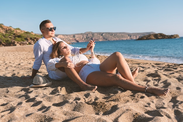 Glückliches verliebtes Paar sitzt bei Sonnenuntergang oder Sonnenaufgang am Strand