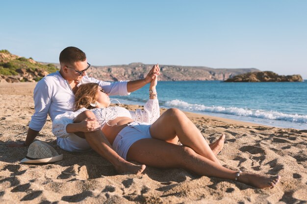 Glückliches verliebtes Paar sitzt bei Sonnenuntergang oder Sonnenaufgang am Strand