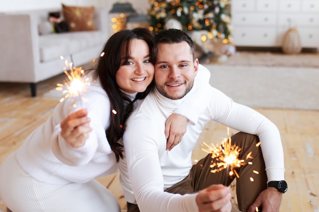 Glückliches Weihnachtskonzept, verliebtes Paar, das durch den Weihnachtsbaum umarmt und küsst