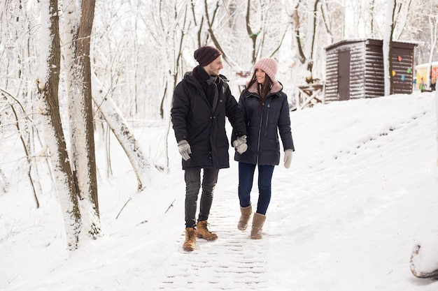 Glückliches Weihnachtspaar in der Liebe, die im kalten Winterwinterwald kalt geht